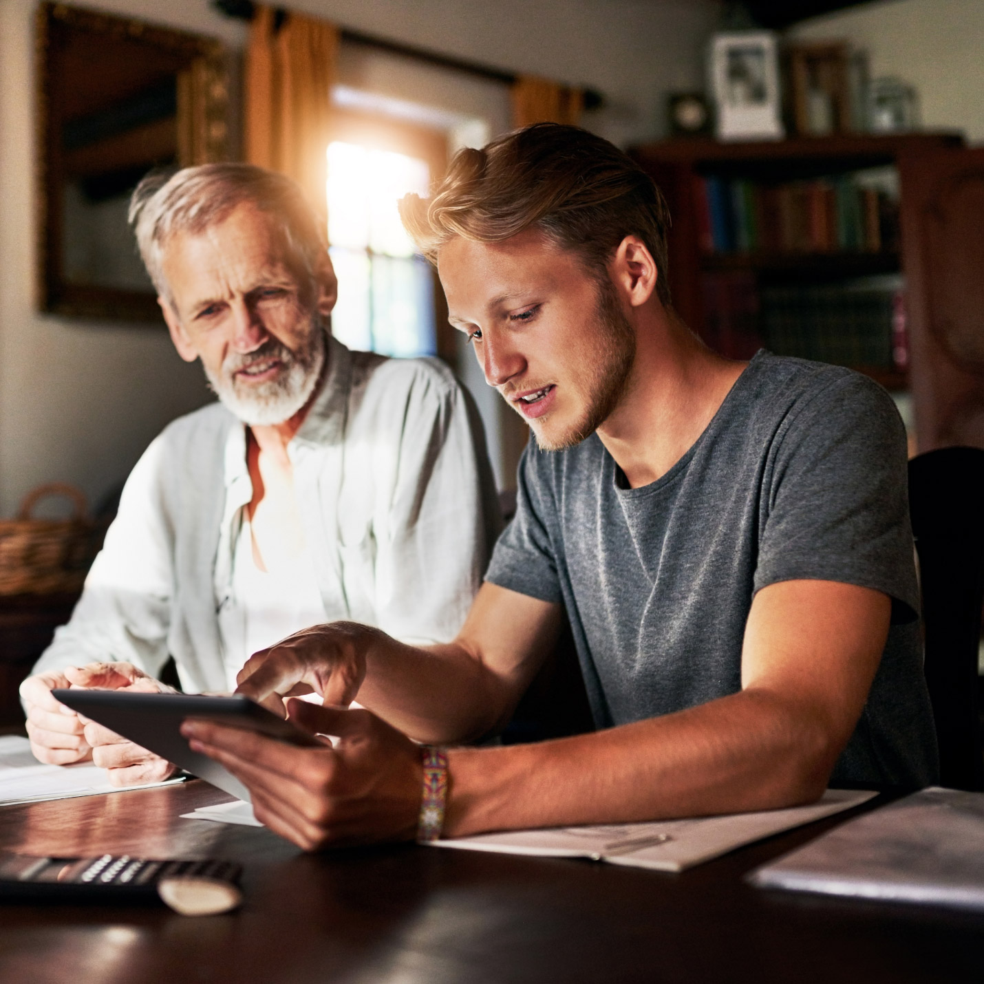father and his recent nursing graduate son sit in their home office reviewing CareScout employer benefits