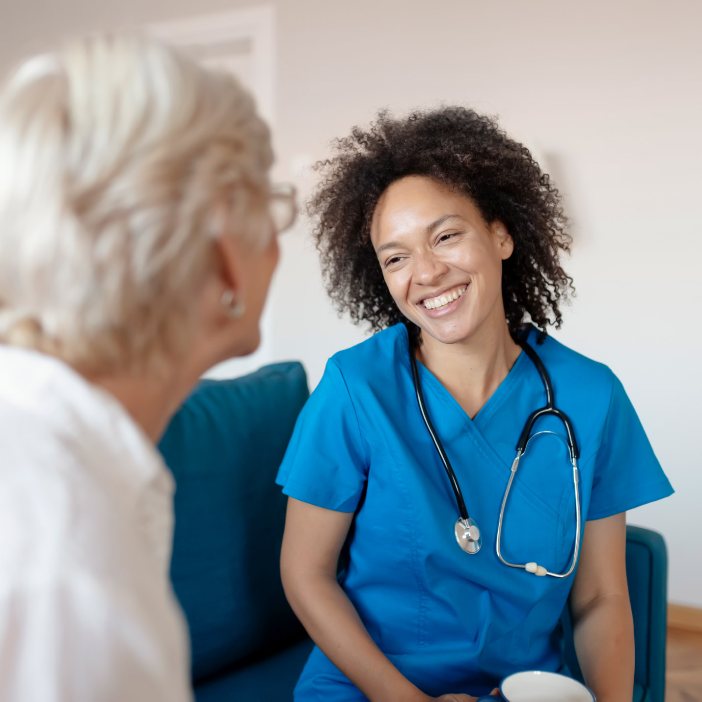focus on in-home care nurse speaking with an elderly woman over the shoulder of the elderly woman out of focus